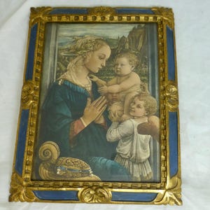 May include: A framed print of a Renaissance-style painting. The artwork depicts a woman in a blue dress with two children. The frame is gold with blue accents. The painting has a landscape background.