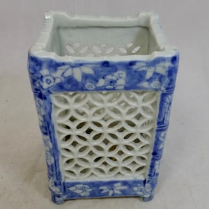 Könnte beinhalten: Eine rechteckige Porzellanvase mit blau-weißem Blumendesign. Die Vase hat ein Gittermuster auf der Vorder- und den Seiten und ist etwa 13 cm hoch.