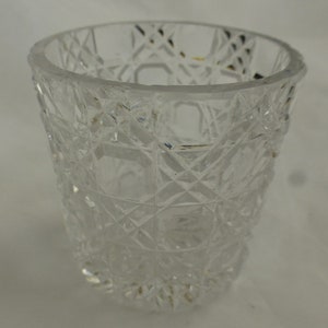 May include: A clear glass vase with a cut glass design. The vase has a wide mouth and a narrow base.