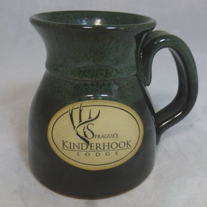 May include: A green and black ceramic mug with a gold oval logo that reads "Prague's Kinderhook Lodge".
