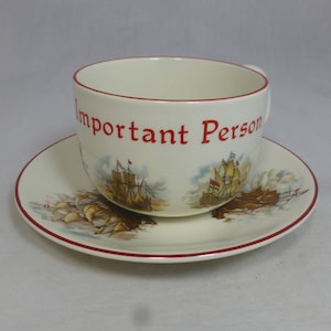 Puede incluir: Una taza de té y un platillo blancos con un borde rojo. La taza de té tiene las palabras "Important Person" impresas en rojo en el lateral. La taza de té y el platillo están decorados con una ilustración colorida de barcos de vela.
