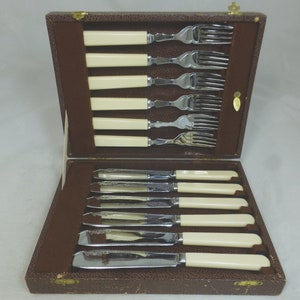 May include: A set of eight silver-plated knives and forks with ivory-coloured handles, in a brown leather case.