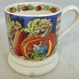 Può includere: Tazza in ceramica con una stravagante illustrazione di un topo che legge all'interno di una zucca. La tazza ha un manico e una base bianchi, con una fascia blu e immagini autunnali di zucche e fogliame. Il testo sul libro recita "100 Ways With Pumpkin."