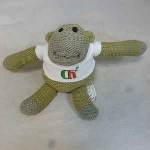 Puede incluir: Un mono de punto verde que lleva una camiseta blanca con el texto "Oh Imp" impreso.