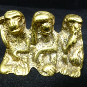 Puede incluir: Escultura dorada que representa a los tres monos sabios: No ver el mal, no oír el mal, no hablar el mal. Los monos están sentados, con las manos cubriendo sus ojos, oídos y boca.