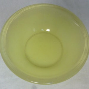 May include: A pale yellow glass bowl with a smooth, rounded rim. The bowl is empty and has a slight sheen.