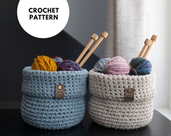 May include: Two crochet baskets, one light blue and one beige, filled with colorful yarn balls and wooden knitting needles. The light blue basket has a leather tag. The text "CROCHET PATTERN" is in a white circle in the upper left.