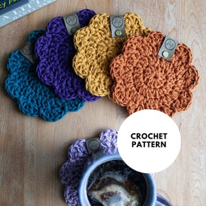 May include: Four crocheted flower-shaped coasters in teal, purple, yellow, and orange. The coasters are arranged in a semi-circle on a wooden surface. A white circle with the text "CROCHET PATTERN" is in the lower right corner of the image.