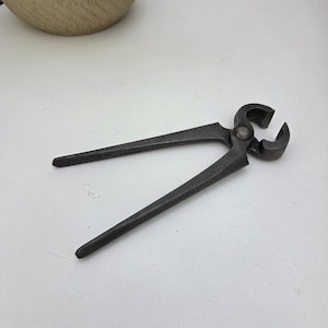May include: A pair of dark grey metal end cutting pliers featuring long, tapered handles and a rounded, heavy-duty jaw mechanism connected by a central pivot pin. The tool has a matte, textured finish and a robust, industrial construction design.