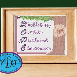 May include: Cross stitch pattern featuring a tree with the words "Huckleberry", "Overbite", "Ticklefoot", and "Dumvacation" written on it. The tree trunk has the word "Hope" carved into it. The pattern is in a wooden frame.