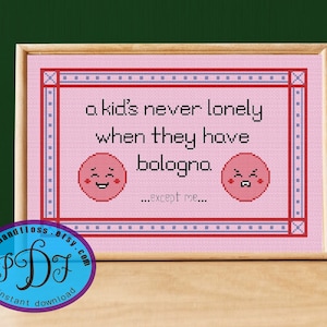 May include: A pink cross-stitch pattern with a white frame. The pattern features the text "a kid's never lonely when they have bologna...except me..." with two cartoon bologna slices with faces.