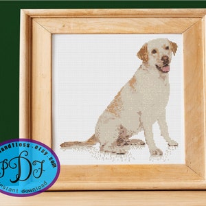 May include: Cross stitch pattern of a white Labrador Retriever sitting with its tongue out. The pattern is in a wooden frame and has a blue and white logo with the text "Stitch and Floss Etsy.com Instant Download".