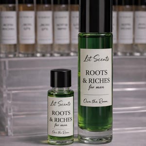 May include: Two glass perfume bottles with black caps. The larger bottle contains green liquid and a label that reads "Lit Scents ROOTS & RICHES for men." The smaller bottle has the same label. The text "Own the Room" is also visible.