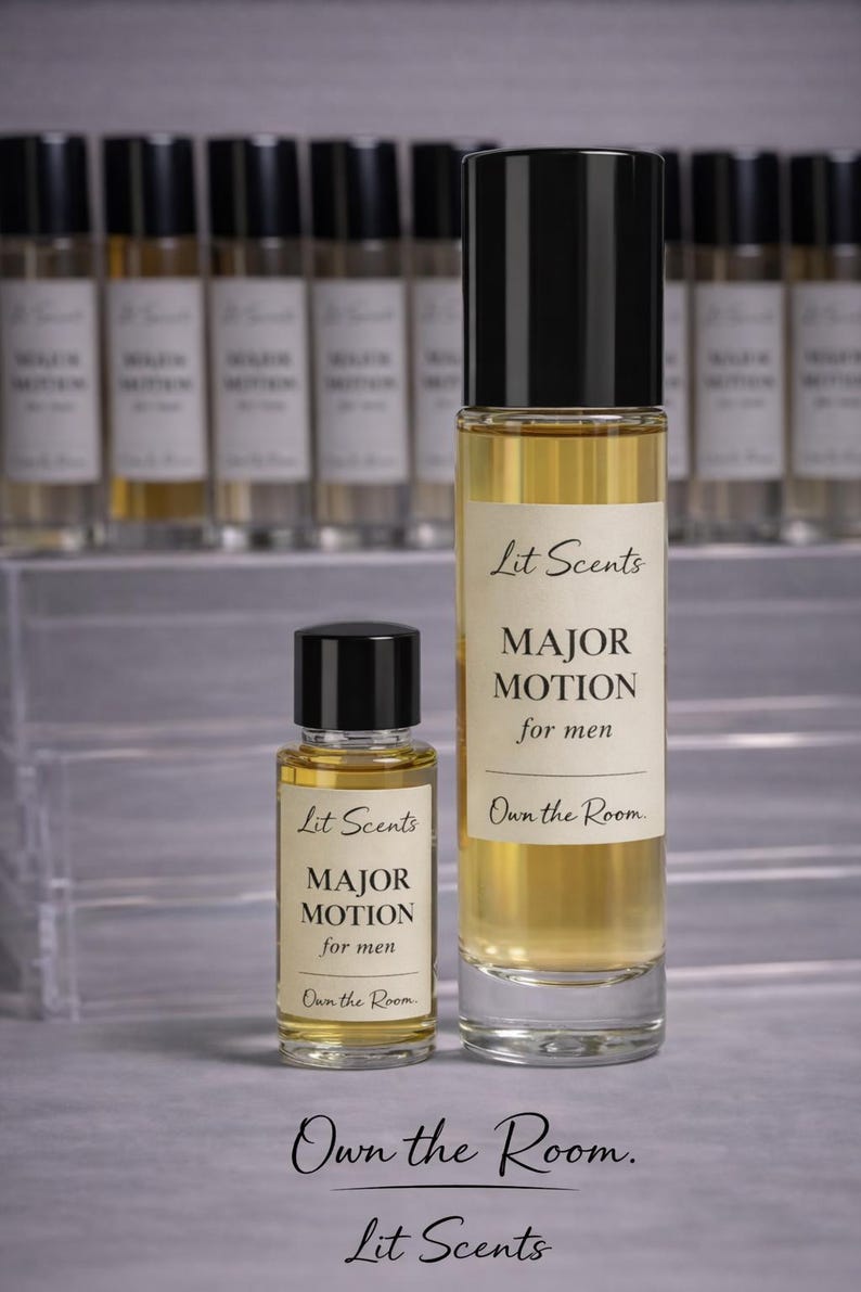May include: Two glass perfume bottles with black caps and labels that read "Lit Scents MAJOR MOTION for men." The bottles are filled with a golden liquid. The text "Own the Room" is also visible.
