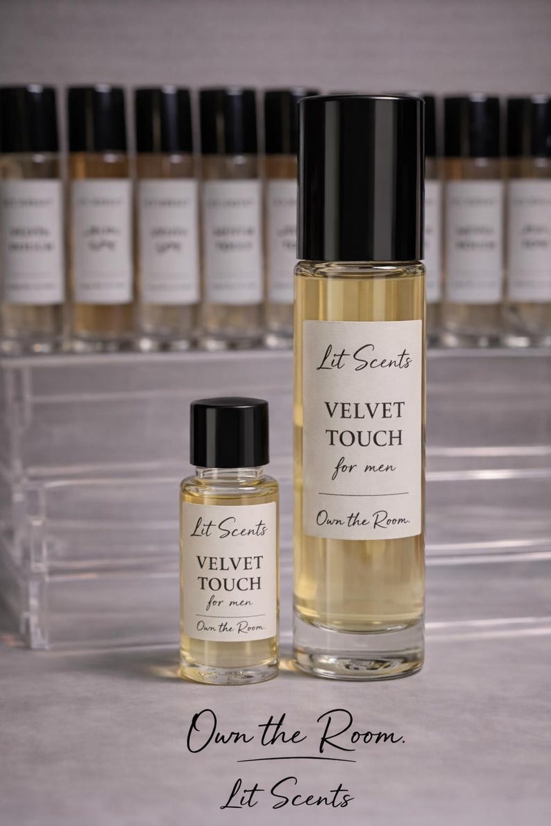 May include: Two perfume bottles with black caps and clear glass, one large and one small, are displayed. The bottles have white labels with the text "Lit Scents VELVET TOUCH for men Own the Room." Additional bottles are in the background.