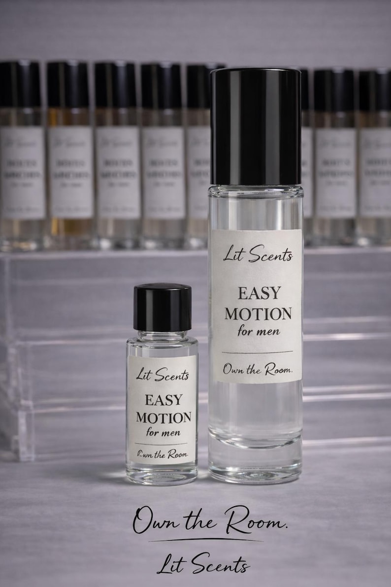 May include: Two clear glass perfume bottles with black caps. The larger bottle has a label that reads "Lit Scents EASY MOTION for men Own the Room." The smaller bottle has the same label. Additional bottles are in the background.