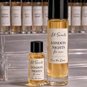 May include: Two glass perfume bottles with black caps, one large and one small, filled with a golden liquid. The labels read "Lit Scents LONDON NIGHTS for men Own the Room." Additional bottles are visible in the background.