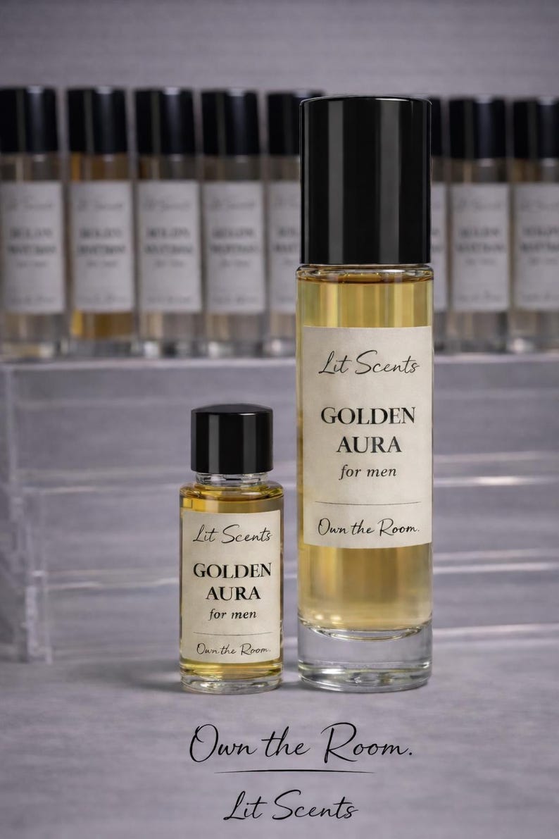 May include: Two glass perfume bottles with black caps, one large and one small, filled with a golden liquid. The labels read "Lit Scents GOLDEN AURA for men." The phrase "Own the Room" is also visible. Other bottles are in the background.