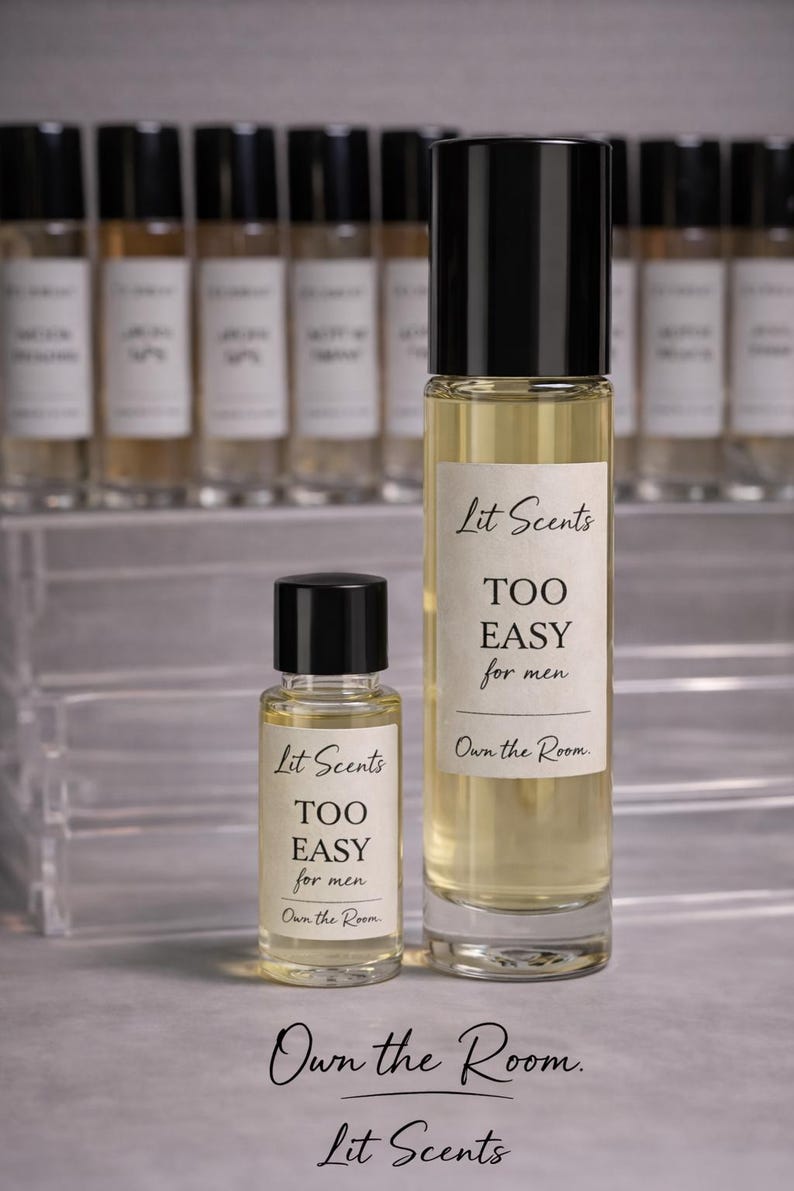 May include: Two glass perfume bottles with black caps, one large and one small, filled with a light yellow liquid. The bottles have white labels with the text "Lit Scents TOO EASY for men" and "Own the Room."