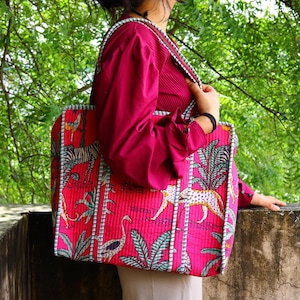 May include: A large, rectangular tote bag with a vibrant pink background and a repeating pattern of zebras, leopards, and tropical plants. The bag has a white and blue striped border and matching straps.