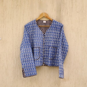 May include: A blue and white patterned jacket with a V-neck and long sleeves. The jacket has two pockets and a button closure.