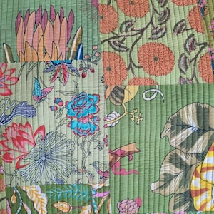 May include: A quilted textile featuring a patchwork design with a light green background. The pattern includes various botanical illustrations such as orange chrysanthemums, pink protea flowers, blue blossoms, and a small butterfly, all stitched with vertical lines.