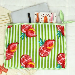 May include: A rectangular quilted fabric pouch featuring a vibrant pattern of red pomegranates and green leaves over a white and green vertical striped background. The pouch has a green and white striped border and a matching green and white striped tie.