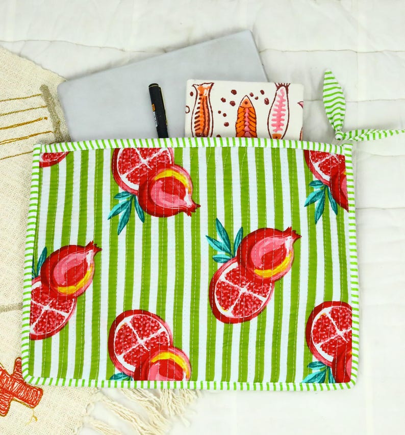 May include: A rectangular quilted fabric pouch featuring a vibrant pattern of red pomegranates and green leaves over a white and green vertical striped background. The pouch has a green and white striped border and a matching green and white striped tie.