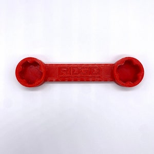 May include: A red wrench with a star-shaped opening on each end. The wrench is labelled "RIDGID".