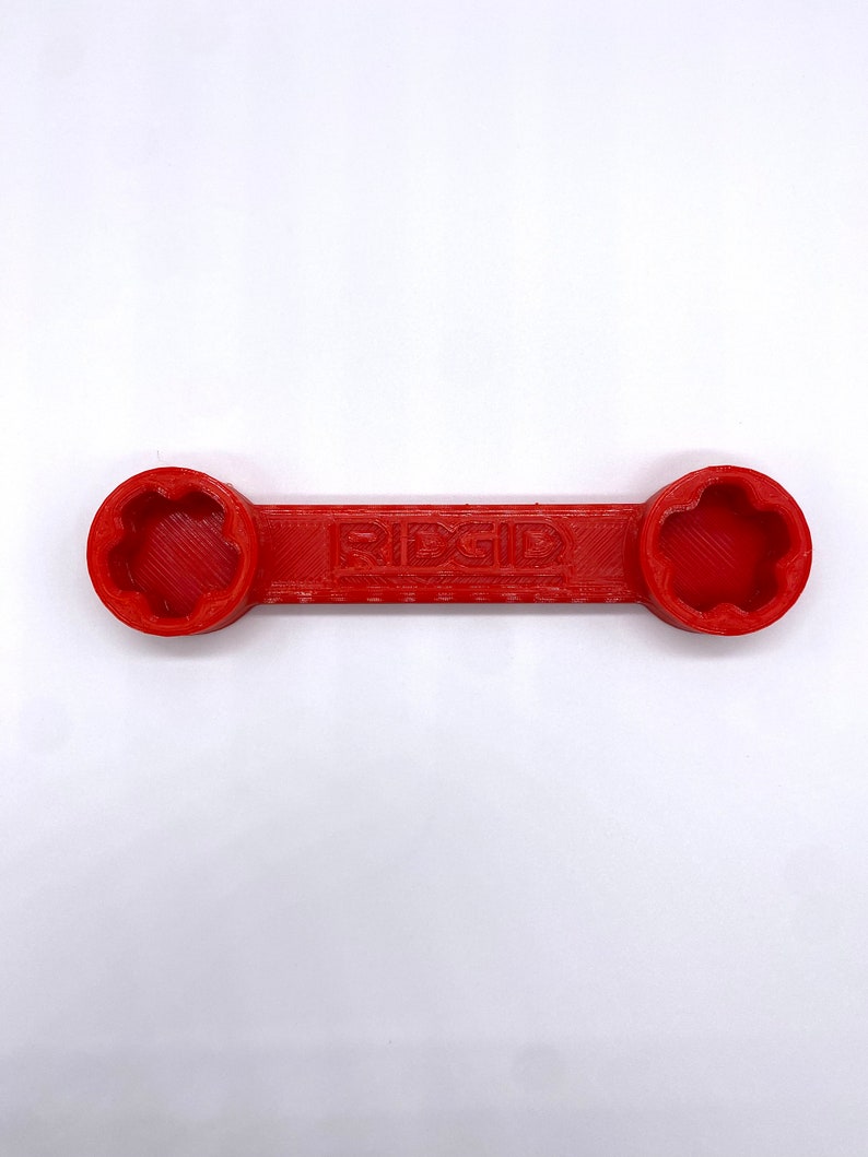 May include: A red wrench with a star-shaped opening on each end. The wrench is labelled "RIDGID".