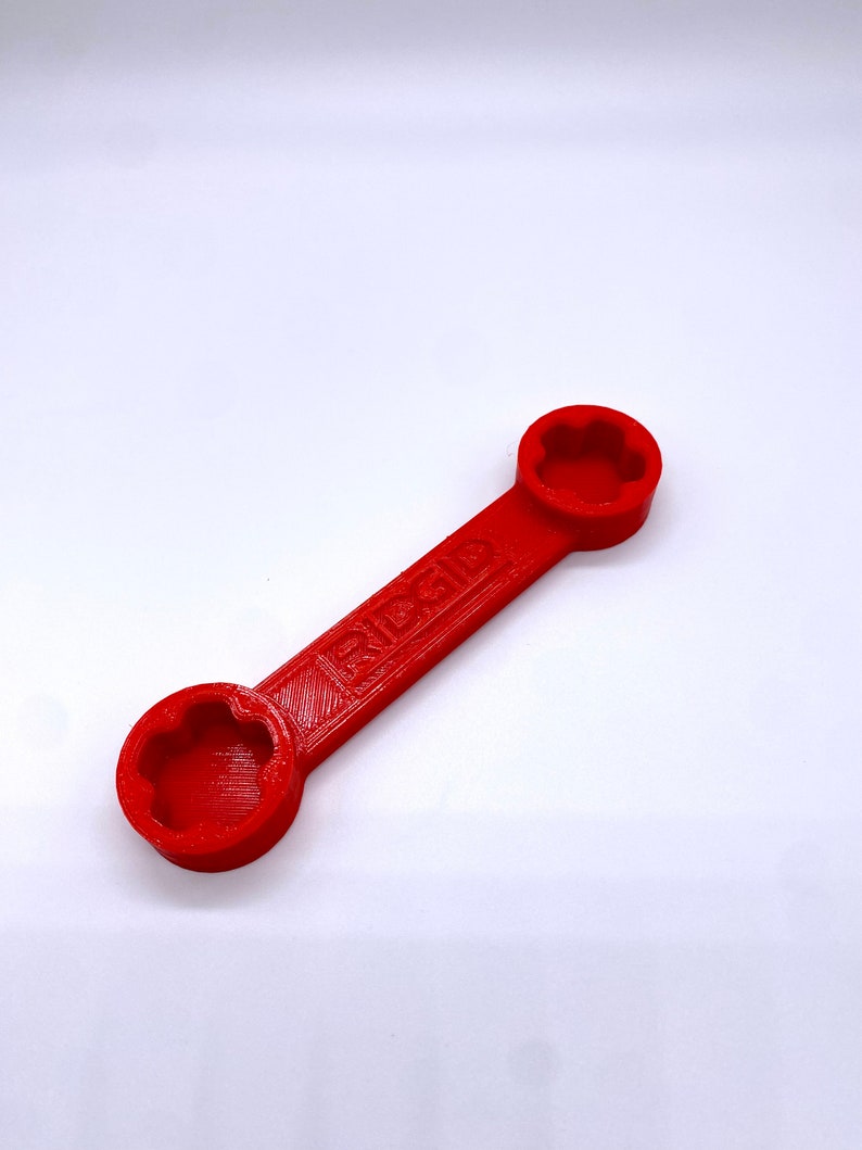 May include: A red wrench with a star-shaped opening on each end. The wrench is labelled "RIGID".