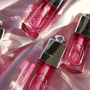 Party favors of Dior Lip Gloss engraved with silver calligraphy with attendees' first names.