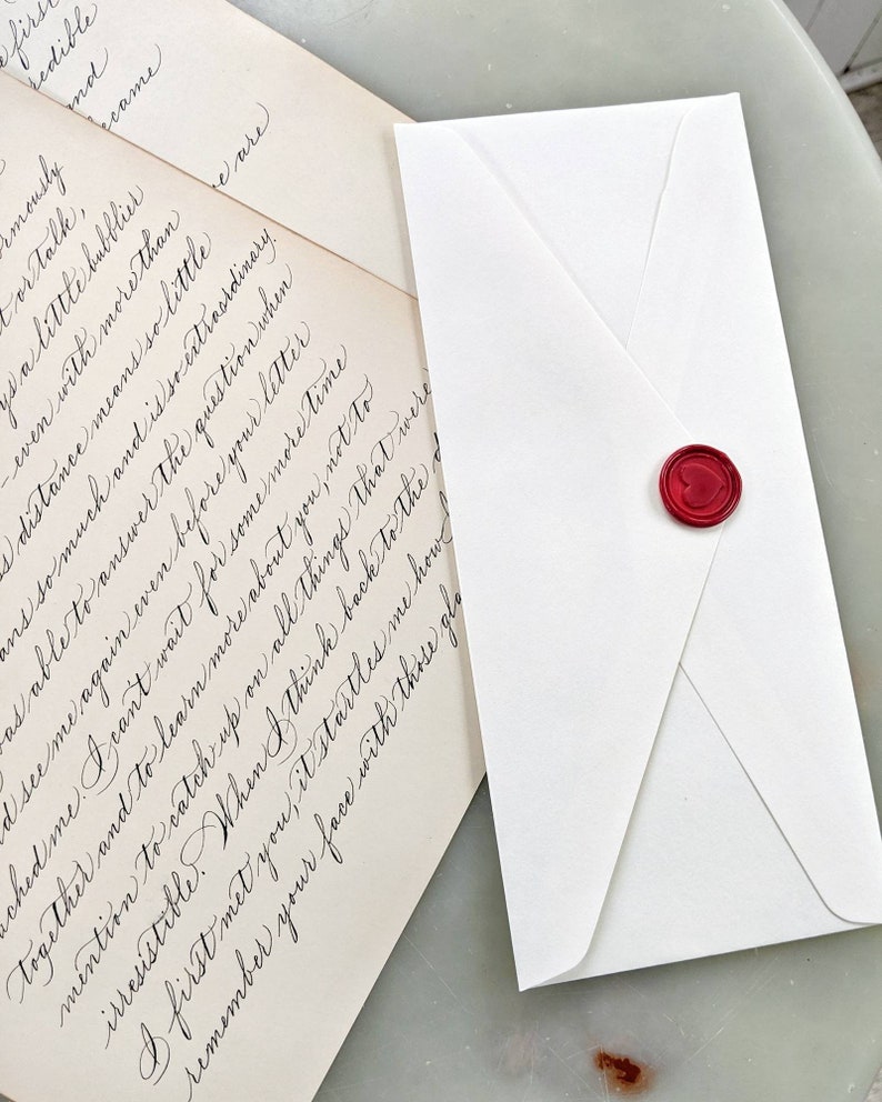 Handwritten love letter in calligraphy on vintage paper with red heart wax seal.