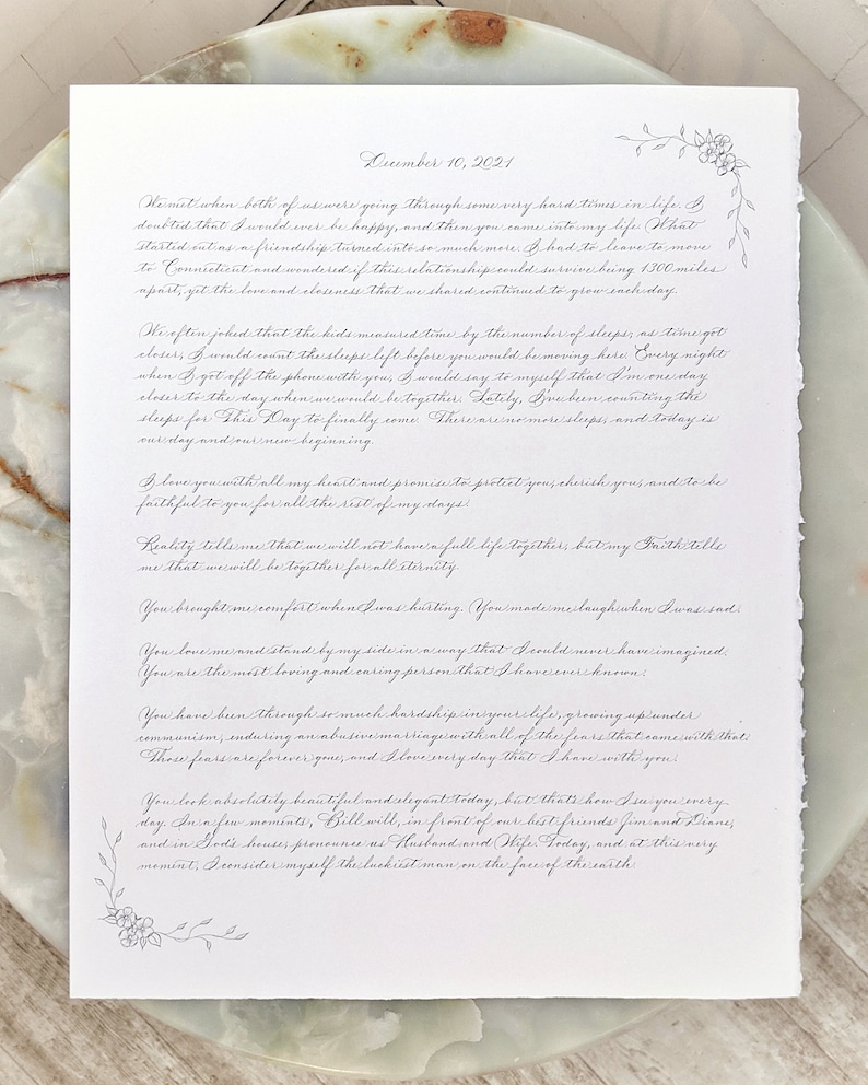 Custom calligraphy wedding vows with the wedding date at the top and floral details in the corners.