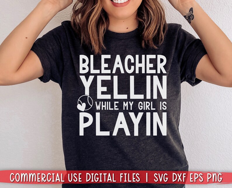 May include: A dark gray t-shirt with white text that reads "Bleacher Yellin While My Girl Is Playin" with a baseball and heart graphic.