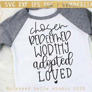 May include: A white t-shirt with a black design that says "chosen redeemed worthy adopted loved" with a small heart at the bottom. The text is in a handwritten style.