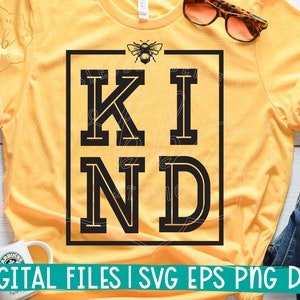 Peut inclure: Un t-shirt jaune avec un graphique carré noir qui dit "KIND" en grandes lettres majuscules. Un petit graphique d'abeille est au-dessus du carré.