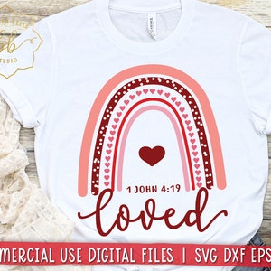 May include: White t-shirt with a red and pink rainbow design and the text "1 John 4:19 loved".