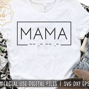 Może przedstawiać: Biała koszulka z czarnym prostokątnym pudełkiem, na którym widnieje napis "MAMA" z linią kresek nad i pod słowem. Tekst "Blessed Belle Studio" znajduje się w małym kółku w lewym górnym rogu obrazu.