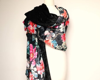 May include: A black velvet scarf with a floral print in shades of pink, blue and green. The scarf is draped over a mannequin.