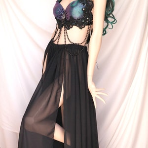 May include: A black sheer maxi skirt with a high slit and a black beaded top with a purple and green iridescent fabric. The top has black lace trim and a beaded chain.