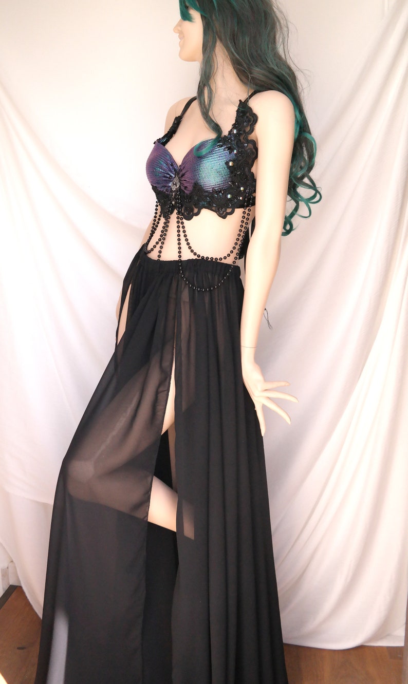 May include: A black sheer maxi skirt with a high slit and a black beaded top with a purple and green iridescent fabric. The top has black lace trim and a beaded chain.
