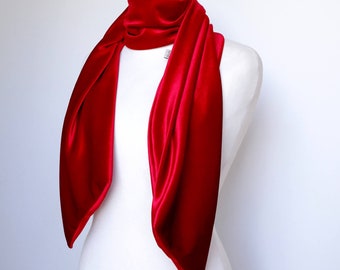 May include: A red velvet scarf draped over a white mannequin. The scarf is long and flowing, with a soft, luxurious texture.