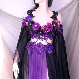 May include: A black and purple fantasy costume with a matching crown. The outfit features a purple bodice with floral accents, a black skirt, and long, flowing sleeves. The crown is black with decorative spikes.