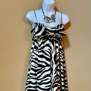 May include: A white and black zebra print dress with thin straps. The dress has a gathered waist and a flowy skirt.