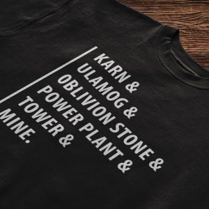 May include: Black sweatshirt with white text that reads "Karn & Ulamog & Oblivion Stone & Power Plant & Tower & Mine."