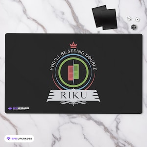 May include: Black playmat with a green, blue, and red circle design. The circle has a crown at the top and the text "You'll be seeing double" around the outside. The text "Riku" is in the center of the circle.