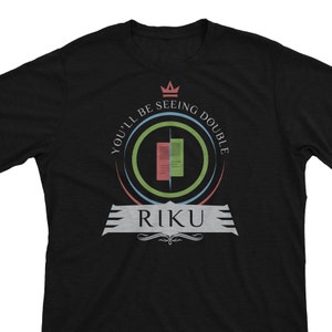 May include: Black t-shirt with a graphic design. The design includes the text "YOU'LL BE SEEING DOUBLE" around a circular graphic with red, green, and blue elements. The name "RIKU" is displayed below the graphic.