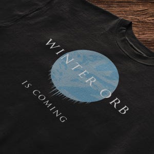May include: Black sweatshirt with a white graphic of a blue orb and the text "Winter Orb" and "Is Coming".