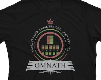 Puede incluir: Camiseta negra con un diseño circular verde y rojo que incluye una corona, el texto "LAND, TRIGGER, LAND, TRIGGER" y la palabra "OMNATH" en fuente plateada.